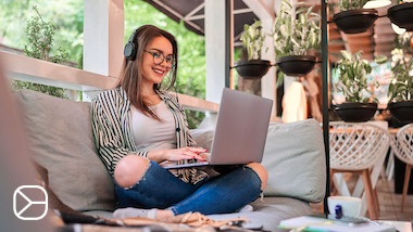 Studentka online kurzu češtiny sedí s laptopem a sluchátky a učí se češtinu.